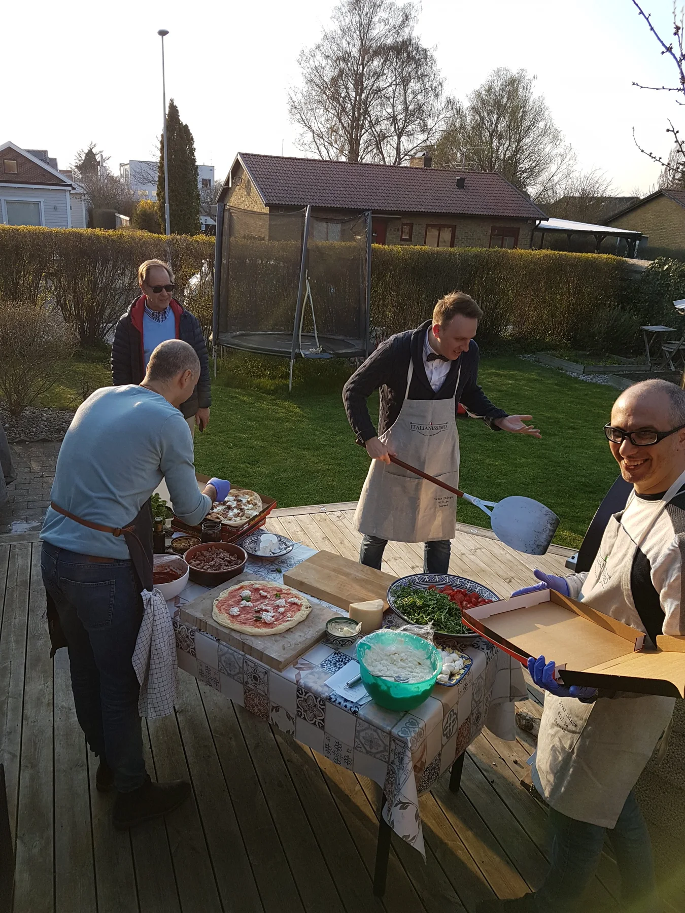 Människor i förkläden lagar pizza tillsammans utomhus